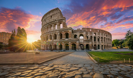 The Colosseum at sunset with colorful clouds in the distance.