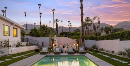 Bel Air pool area with illuminated plunge pool, poolside chairs, palm trees, and a colorful sunset.