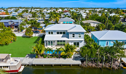 A two-story home situated along the water with a dock out front.