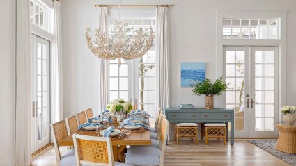 White-walled dining room with wooden floors, stylish furnishings and an elegant chandelier