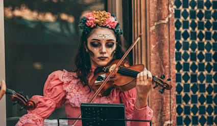 A woman in traditional make up and dress playing the violin.