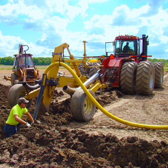 A farmer or earthworks contractor lays drainage tile to help with water management on the farm.