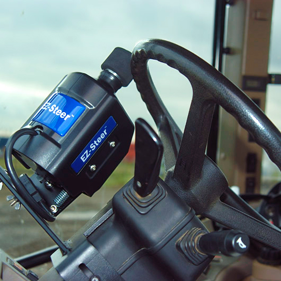 An image showing the inside of the tractor cab with Trimble's EZ-Steer assisted steering system installed on the steering wheel.