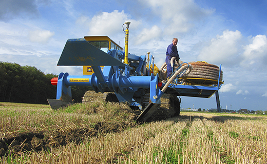 A farmer or earthworks contractor uses the WM-Drain solution to lay drainage tile in their field.