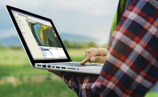 A farmer uses WM-Subsurface design software on a laptop.