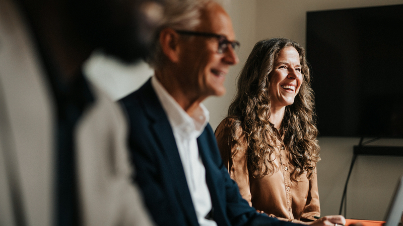 En man och en kvinna sitter bredvid varandra vid ett konferensbord.
