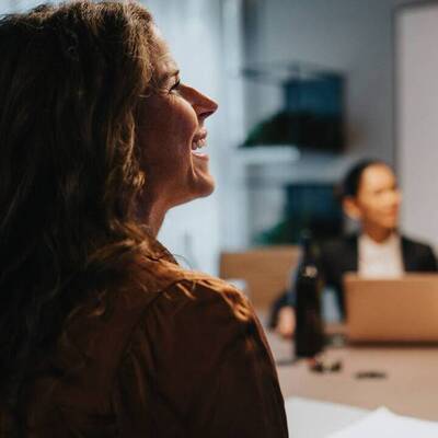 Två kvinnor i mötesrum på kontor med laptops.
