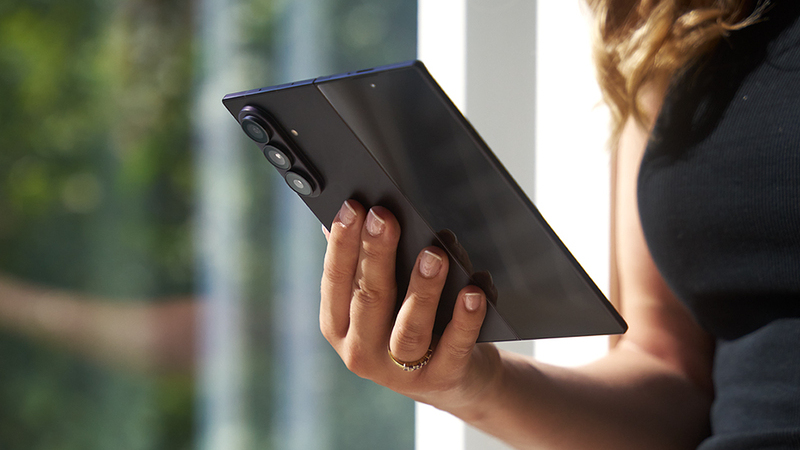Närbild på hand som håller en uppvikt smartphone med en mörk skärm samt en svart baksida med tre kameror.