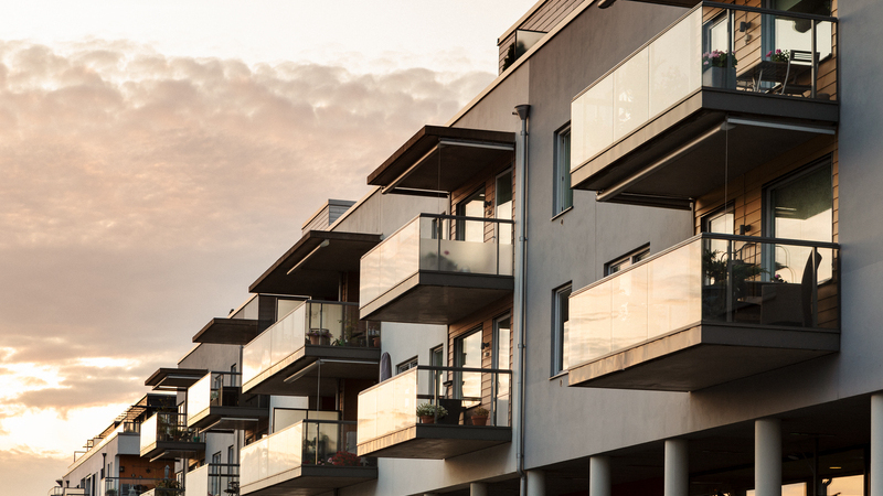 Modernt bostadshus med lägenheter och balkonger med glasräcken.