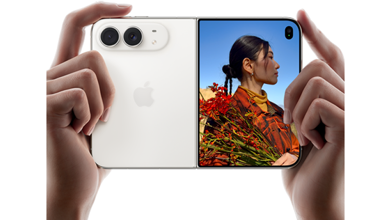 Två händer håller en vit iPhone Duo horisontellt som en traditionell kamera, med baksidan och skärmen synliga. Skärmen visar en kvinna med röda blommor.