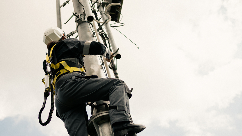 En tekniker klättrar uppför en mast.