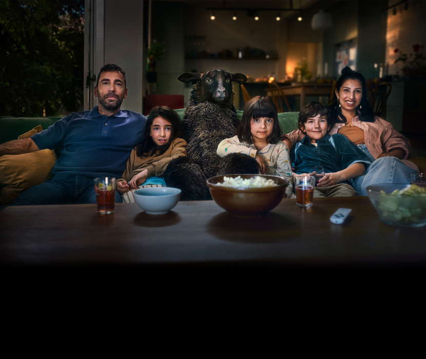 Fåret Frank sitter i soffan med sin familj och tittar på tv