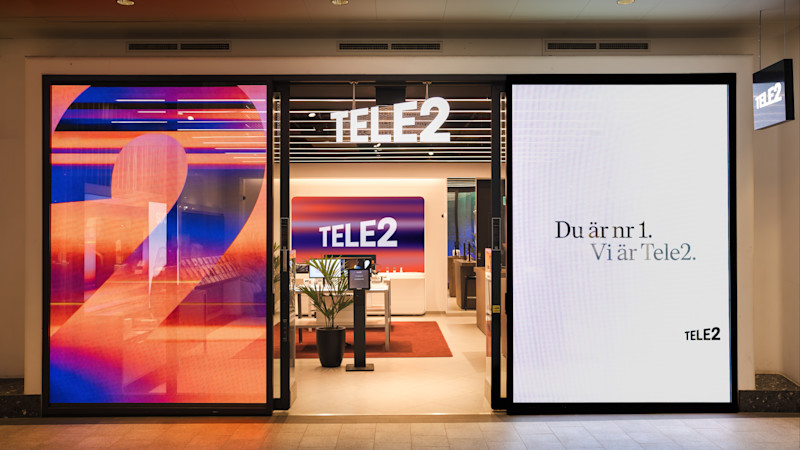 Tele2-butik med färgglad ingång, logotyp och slogan "Du är nr 1. Vi är Tele2." på digitala skärmar.