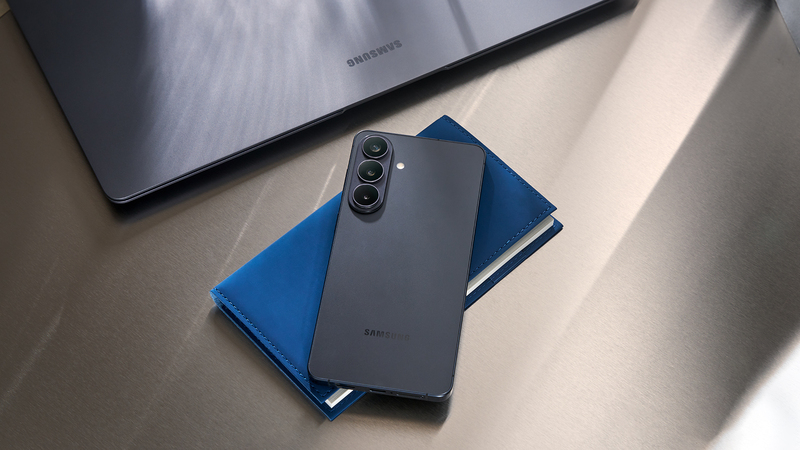 En svart Galaxy S26+-mobil ligger på ett skrivbord med en kalender och en laptop.