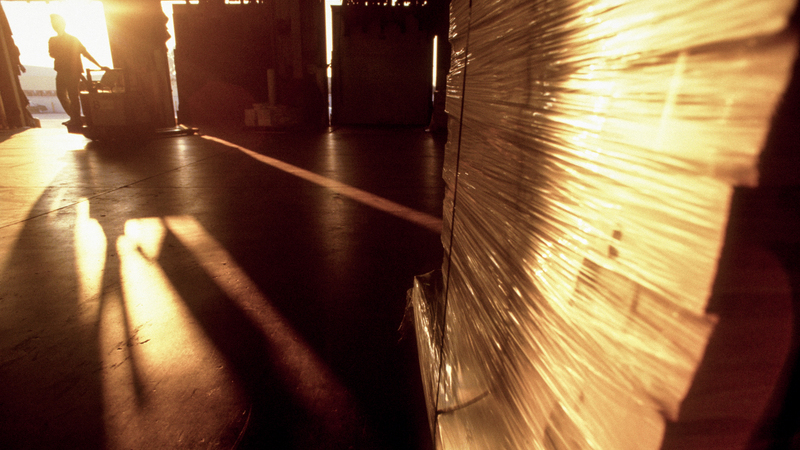 Lagerlokal med silhuett av lagerarbetare i solljus.