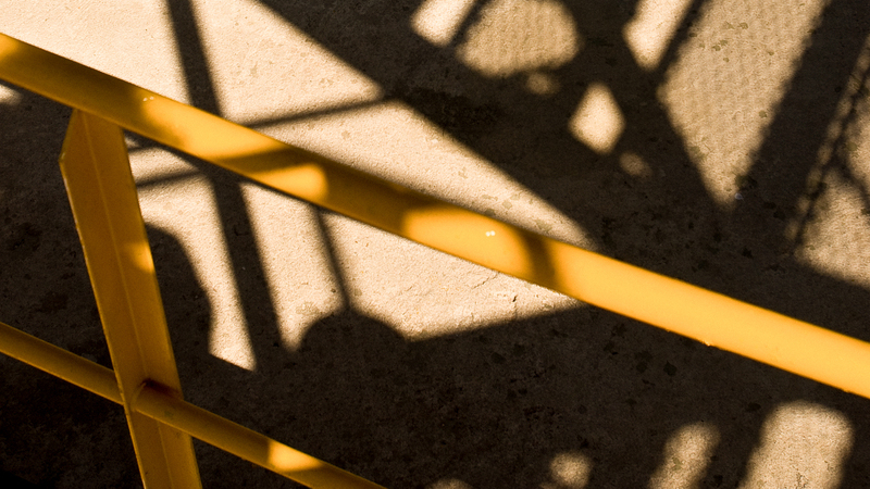 Skugga samt del av gul byggnadsställning.