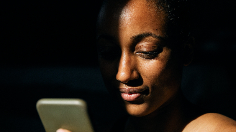 Närbild av ung kvinna som tittar på en mobiltelefon.