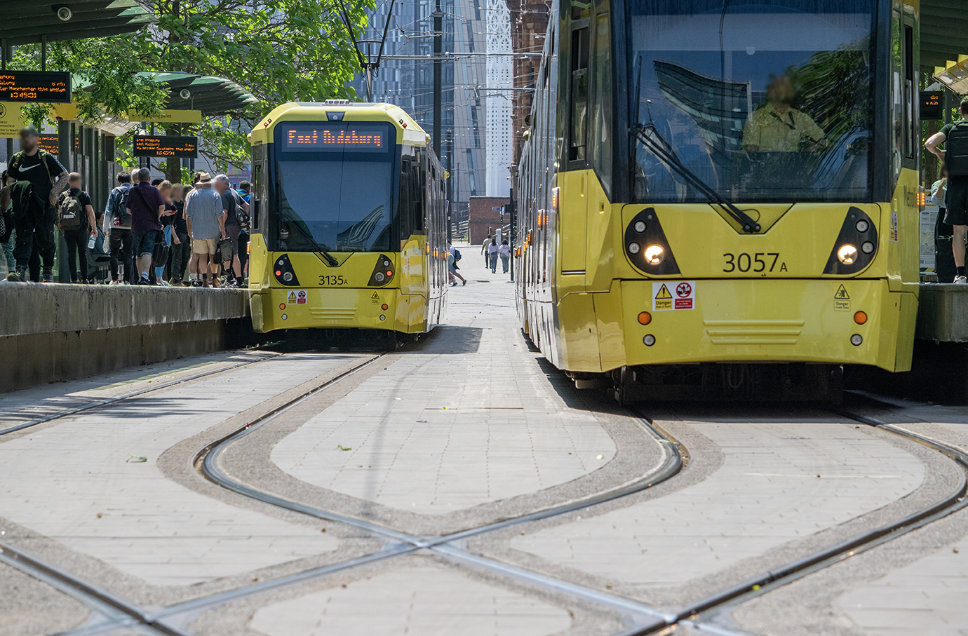 Two metrolink trams at stops in Manchester 