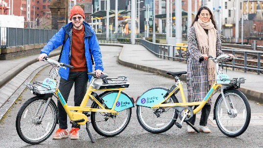 Two people stood with Starling bank bikes in Manchester