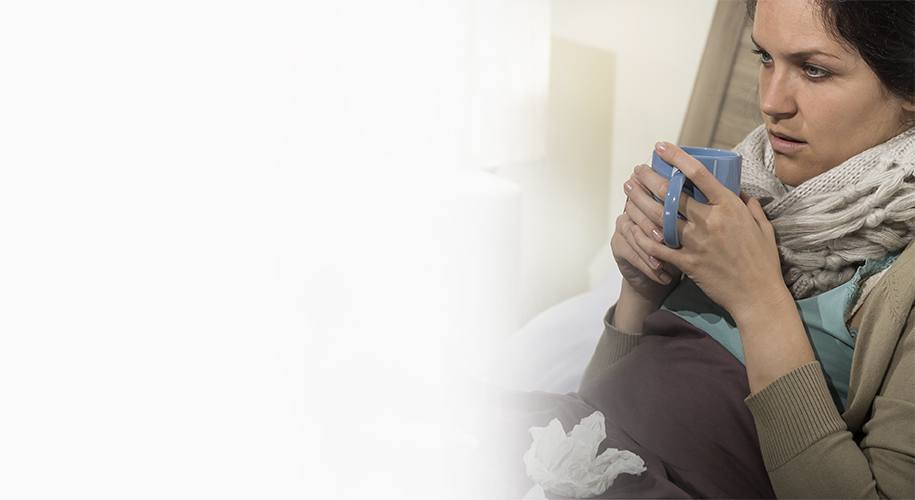 Desktop Symptoms101 Cold Section3 A woman sips tea with tissues in her lap