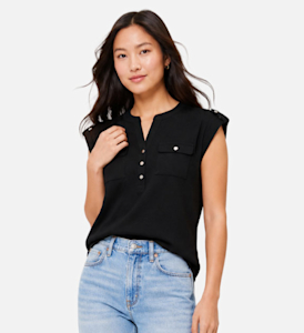 A model wearing a black cap sleeve top with gold accent buttons and blue jeans.