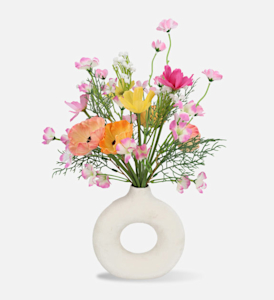 A white circle vase with colourful artificial flowers.