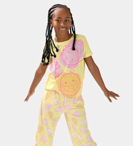 A girl wearing yellow Squishmallow print pyjamas.