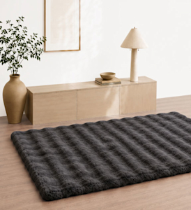 A 4 foot x 6 foot plush black rug in a living room setting on hardwood floors.