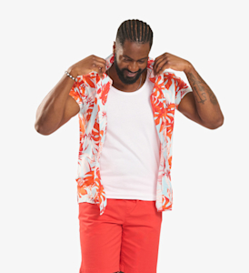male model wearing white and orange tropical printed top with a white t-shirt and orange shorts