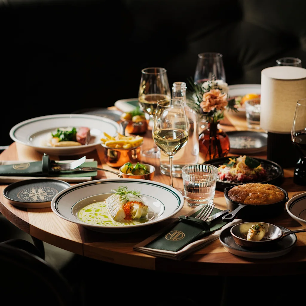 An inviting dining table laden with exquisite dishes, wine, and elegant place settings, ready for a delightful meal.