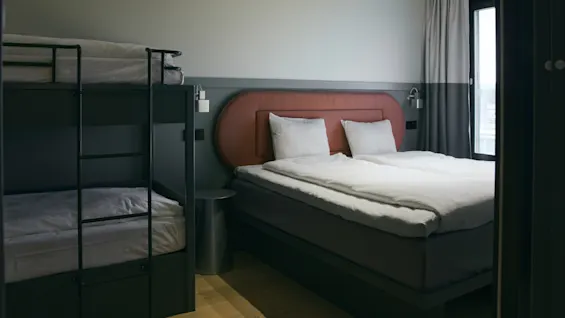 Ett modernt hotellrum på Stopover Hotel Falkenberg med en bekväm dubbelsäng och en våningssäng, perfekt för familjer.