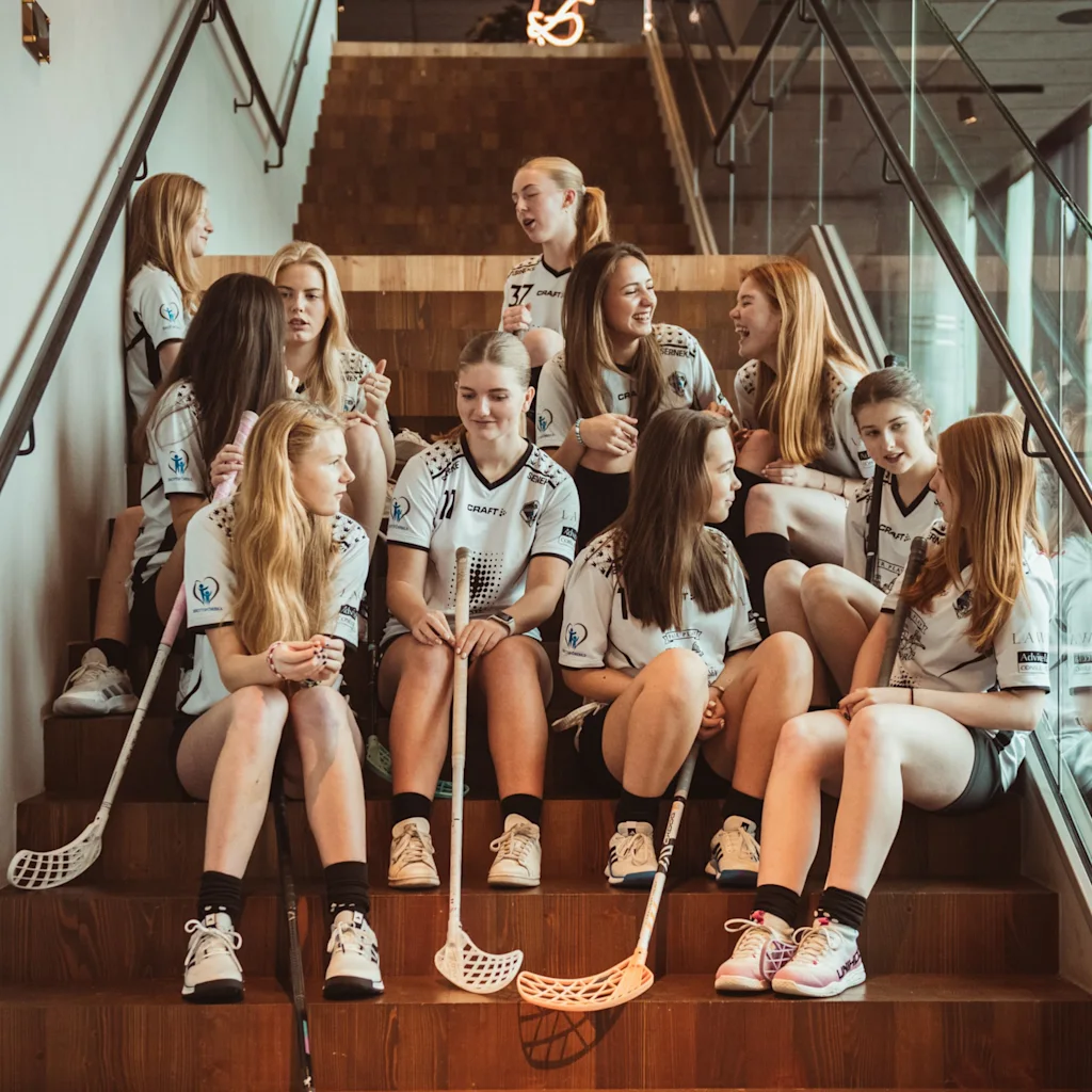 Et innebandylag i uniform slapper av og prater i en moderne tretrapp.