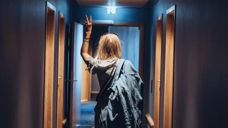 En ung kvinde går gennem en hotelkrridor med ryggen til kameraet. 