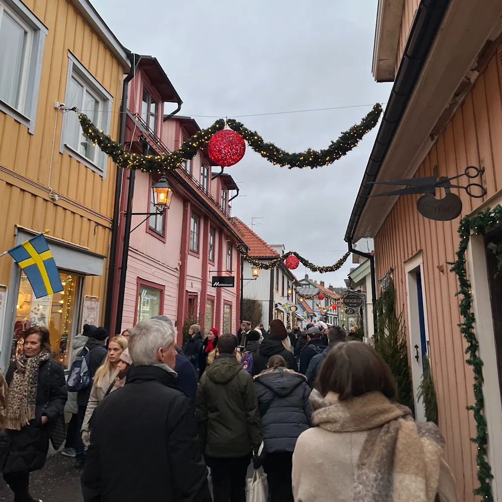 Folk der går ned ad en hyggelig gade pyntet med juleguirlander og lys