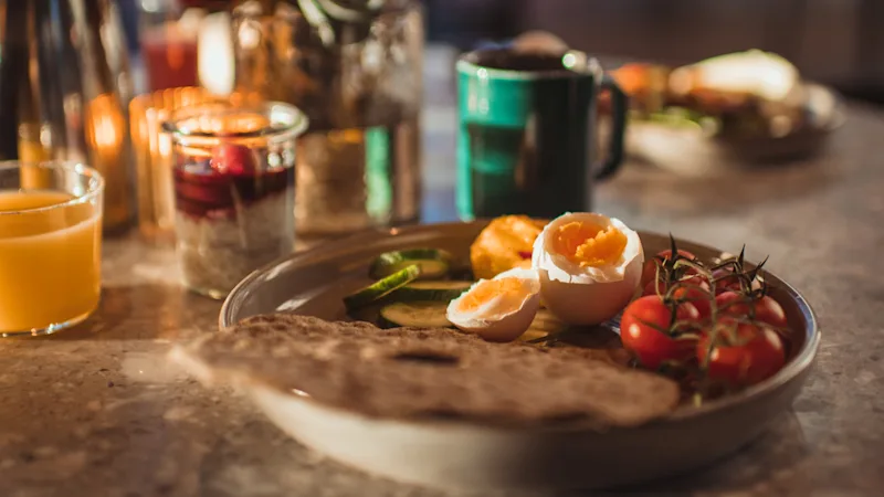 Plate with egg, crisp, tomatoes - orange juice and coffee cup