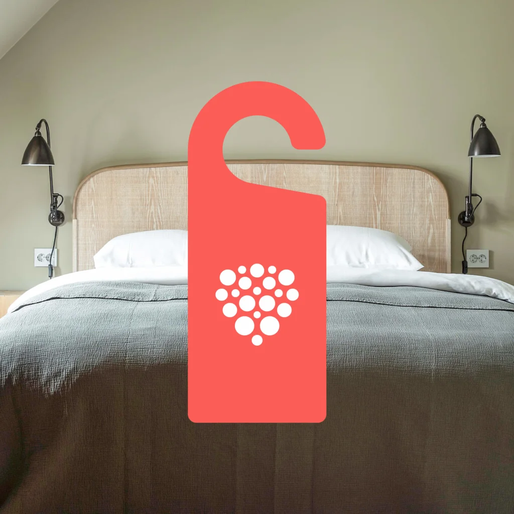 A hotel bed with a door hanger in the front.