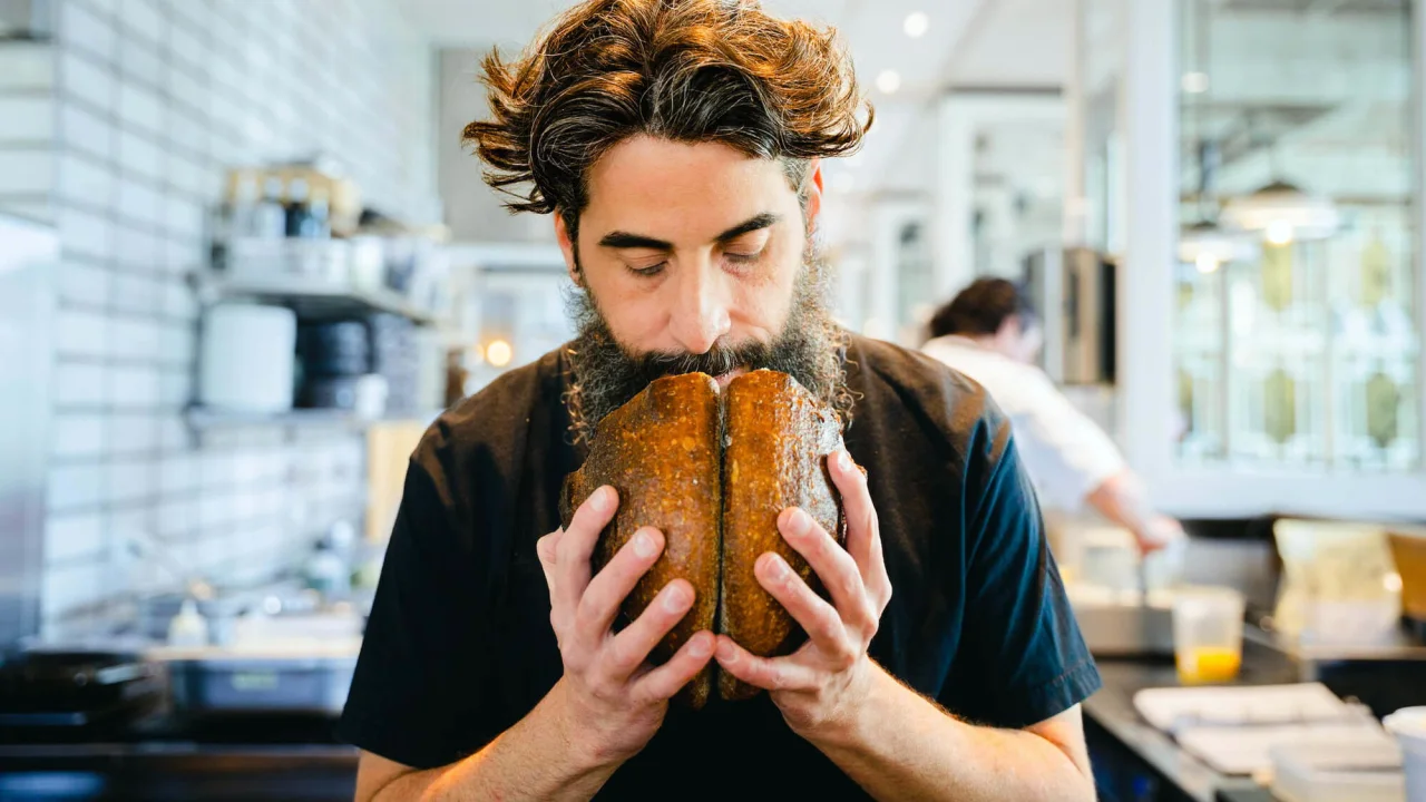 Guy smelling a freshly baked bread at a bakery.