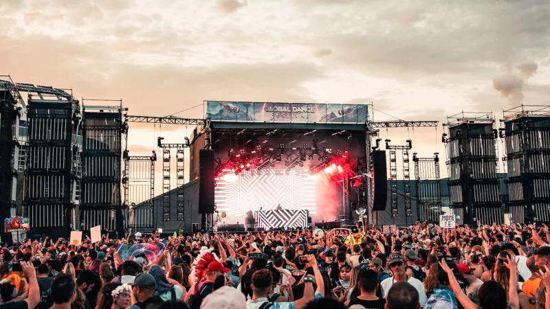 A concert with a lot of people in the sunset.