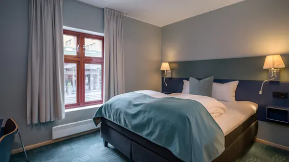 Compact dubbelrum på Quality Hotel Tønsberg med en bekväm säng, sänglampor och ett fönster med gardiner.