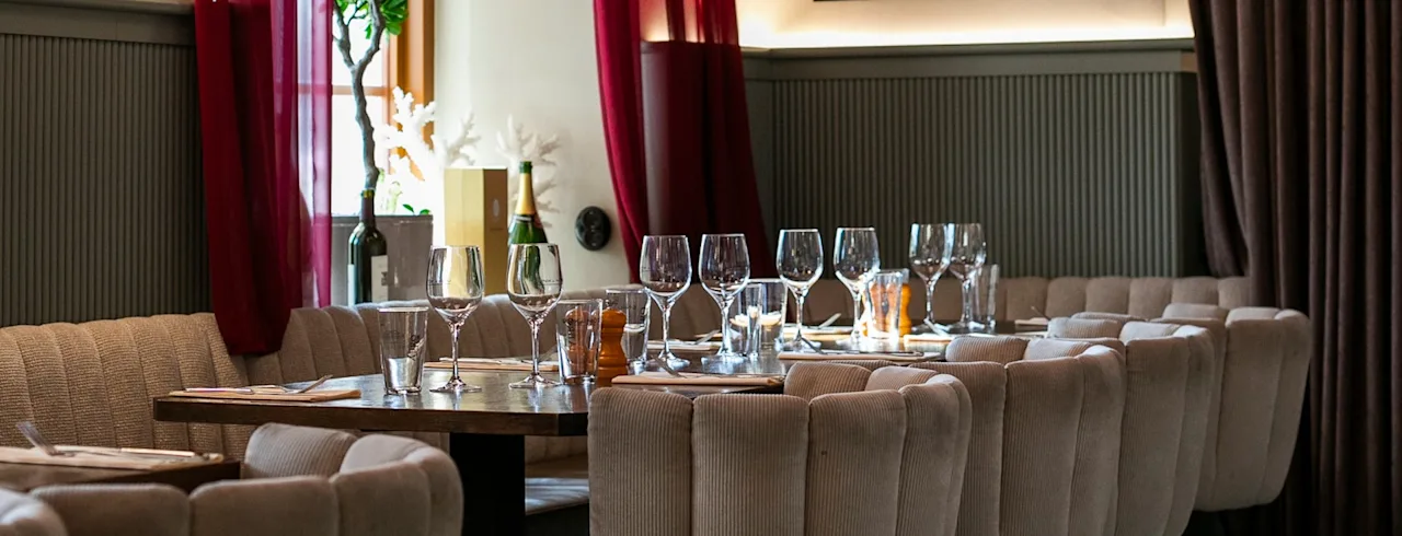 Et stilfuldt restaurantområde med dækkede borde, elegante røde gardiner og moderne belysning.