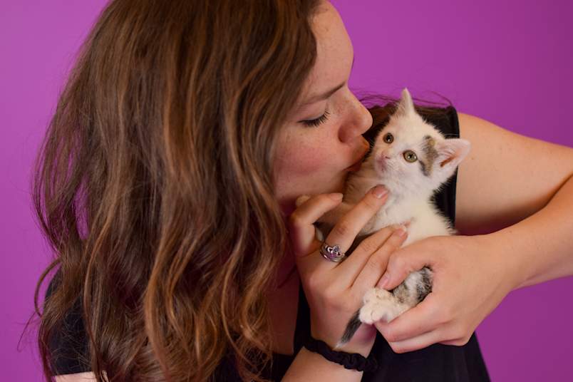 a woman kissing a kitten with a long life span in front of it