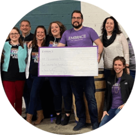 Embrace employees holding a charity check