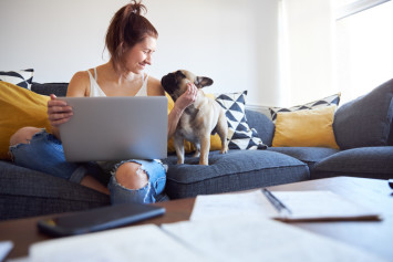 A woman on a couch with her dog in an apartment
