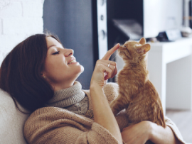 woman booping orange cat on nose