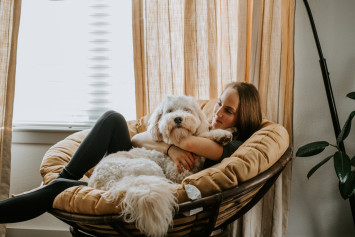 A hypoallergenic dog sitting with it's owner in a chair
