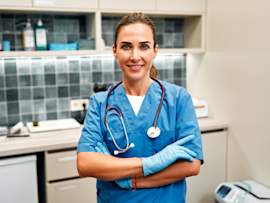 A confident veterinarian in blue scrubs and latex gloves stands with arms crossed in a well-equipped exam room, stethoscope around her neck. Understanding veterinary terminology can make a real difference when discussing your pet's health with a professional. From basic veterinary terminology like "prognosis" and "auscultation" to more complex veterinary medical terminology used in diagnoses and treatment plans, knowing common vet words helps pet owners ask better questions and make more informed decisions.