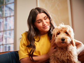 A pet owner sitting with their dog teaching them not to bark