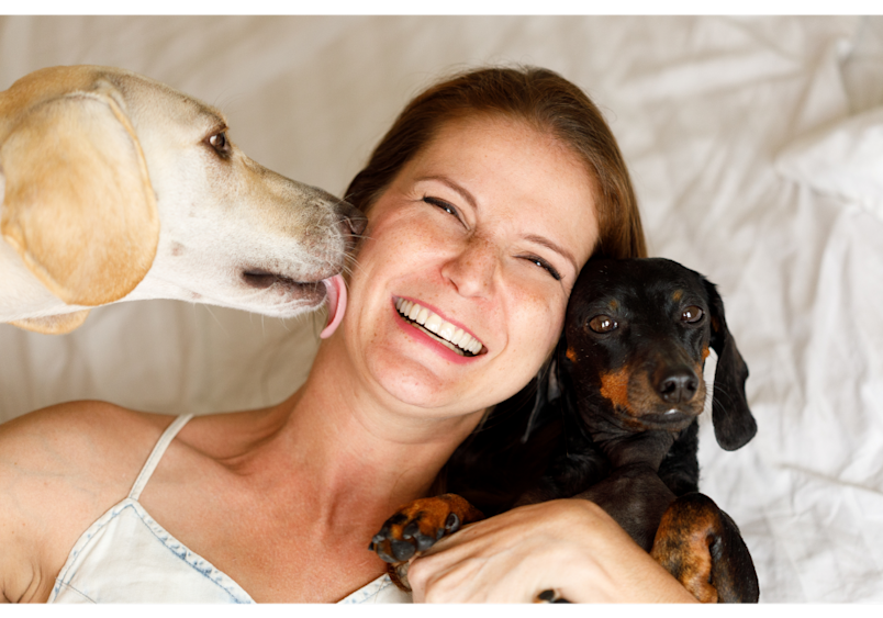shows a woman enjoying affectionate licks from her dog, illustrating how attention-seeking behavior is another frequent cause of licking issues in pets