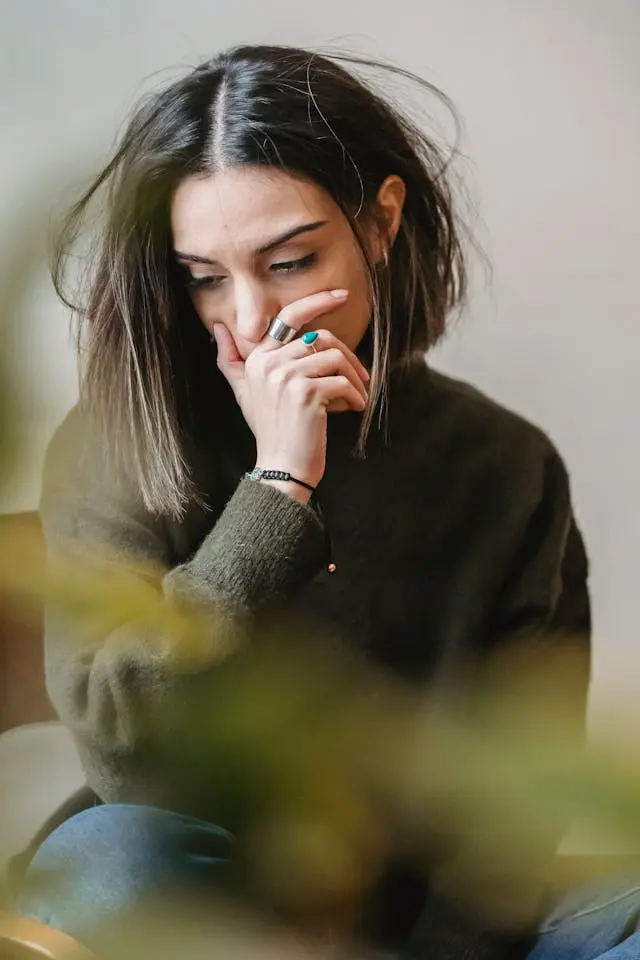 Worry and Stress Anxiety Symptoms Woman sitting alone, looking troubled, with her hair disheveled.