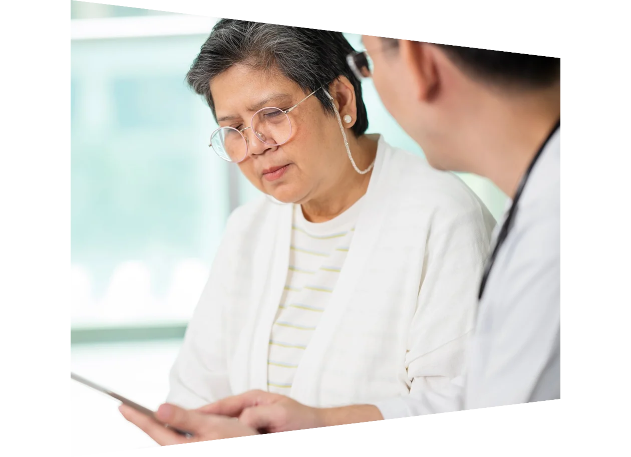 Senior doctor discussing with man over tablet PC in hospital
